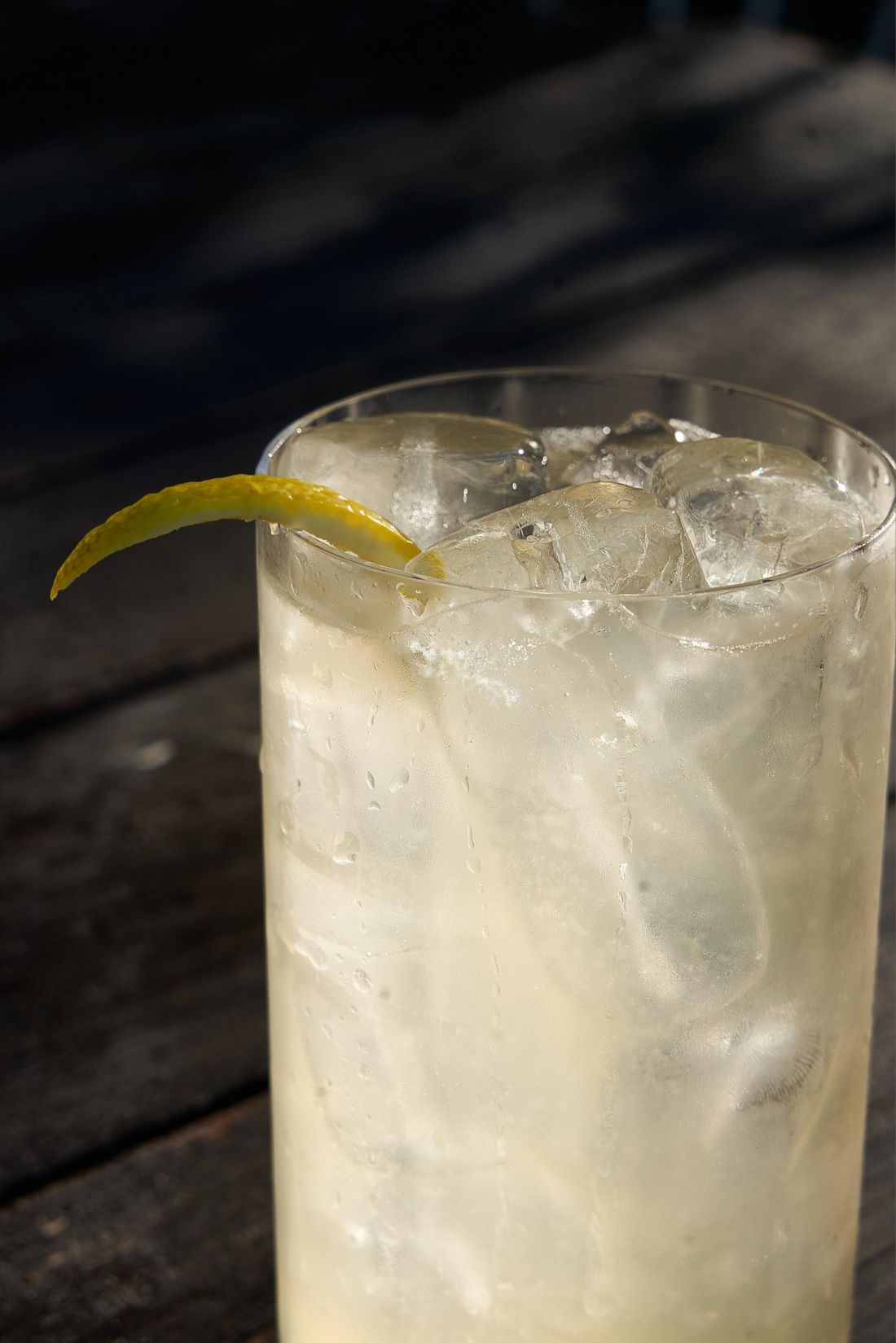 Cocktail chiaro con ghiaccio e scorza di limone