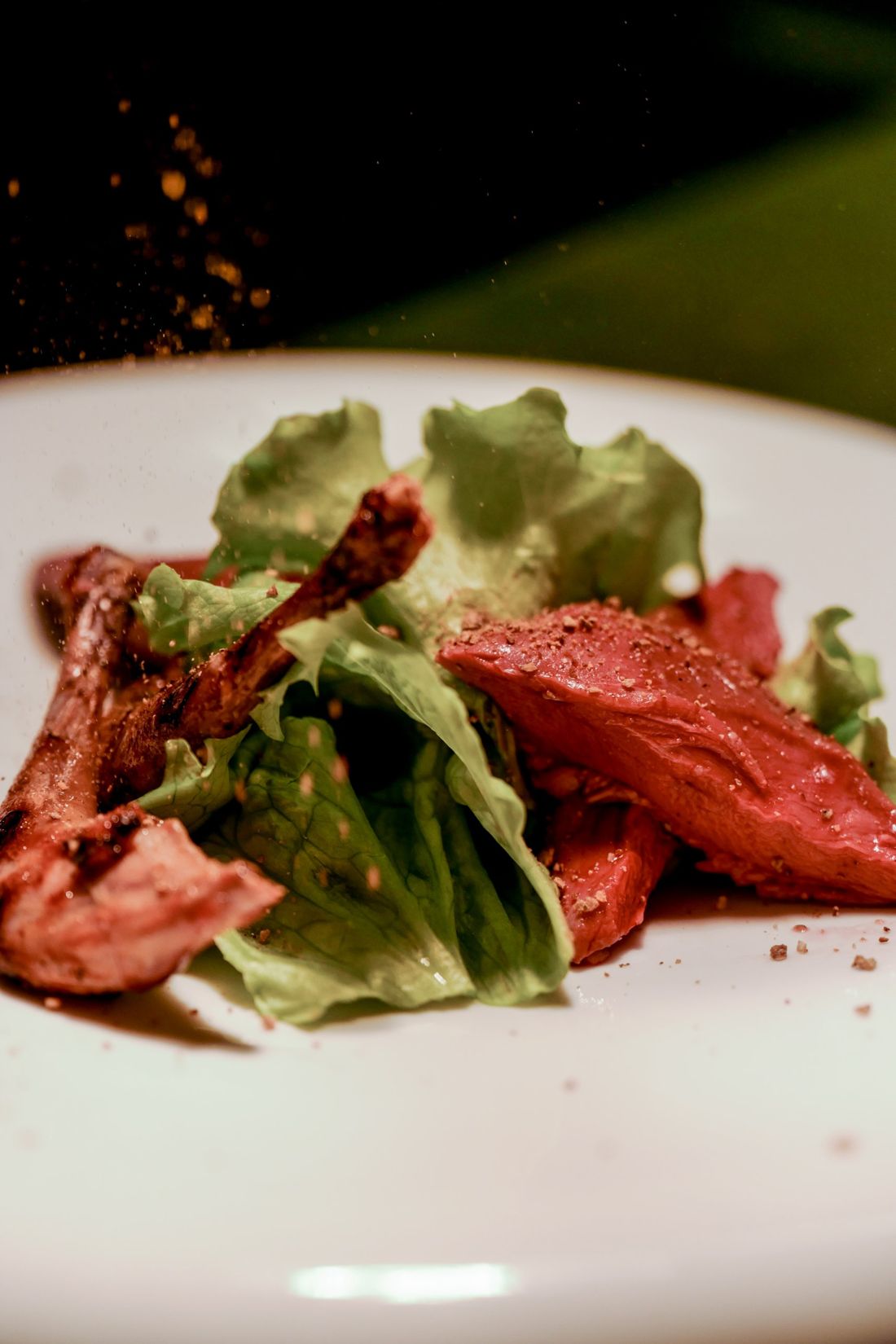 Piatto di carne e insalata, con le spezie che cadono sul piatto